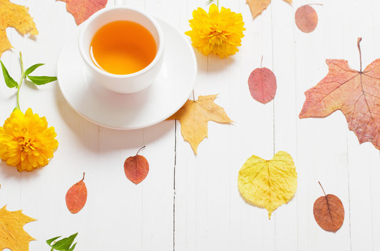 cup of tea with autumn leaves on wooden background