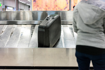 A traveler waiting for a luggage on the belt at the airport.