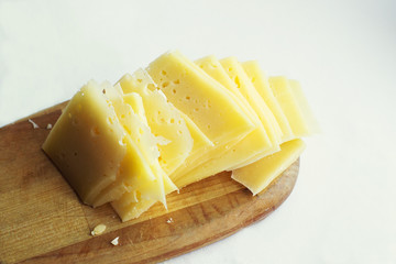 Pieces of the cut cheese on a wooden board.