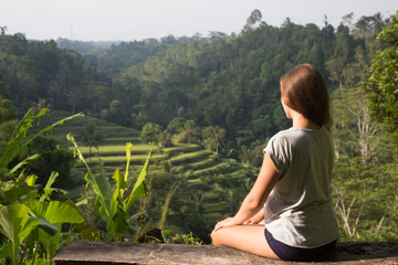 Young woman sitting on the bench and looking at beautiful rice terrace in Bali, Indonesia © Sokirlov