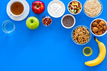 Obraz na płótnie Canvas Make a menu for wholesome breakfast. Fruits, oatmeal, yogurt, nuts, crispbreads, chia on blue background top view copy space
