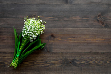 May flowers. Bouqet of lily of the valley flowers on dark wooden background top view copy space