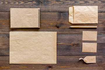 Mockup business brand template. Blank stationery and accessories made of craft paper for branding on dark wooden background top view mockup pattern