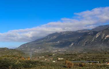 Panorama of mountain valley in Taygetos range on Peloponnese peninsula in Greece, with olive prunning fire and solar farm