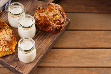 Jars with milk and bread buns on a cutting board 