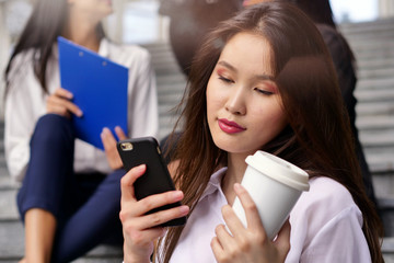 Portrait of a oriental business woman, in a suit and tie, happy and smiling and in the background a group of multi-ethnic business people. Concept of: success, finance and female career,