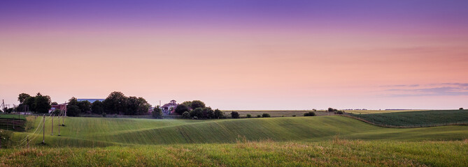 Scenic landscape during sunset. Multicolored sky. Agricultural land against  background of  evening sky. Summer evening landscape is  symbol of peace and tranquility_