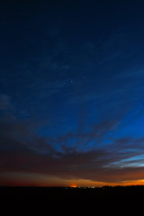 Night sky with stars. A bright sunset with clouds. Cosmic space above the earth's surface. Long exposure.