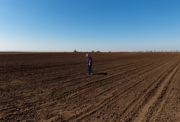 Naklejka na ściany i meble Senior farmer standing in field examining sowing.