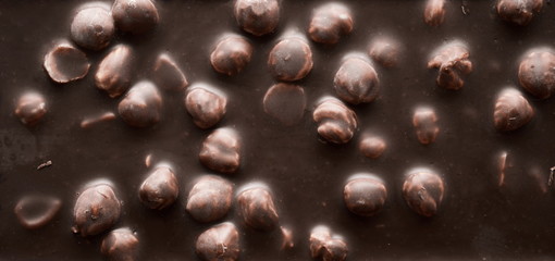 Texture of the chocolate with nuts. Dark chocolate with hazelnuts, background. Flat lay, top view 