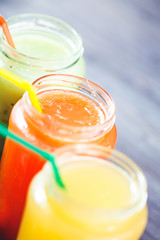 freshly squeezed fruit juice, smoothies yellow orange green blue banana lemon apple orange kiwi grape strawberry on a dark wooden background Close up