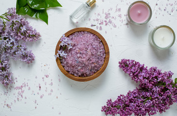 Fototapeta na wymiar Lilac bath salt with lilac flowers and candles top view