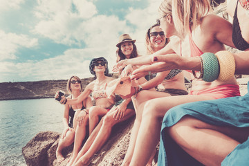 vintage filter for group of beautiful young ladies at the rocky beach taking sun near the ocean and...