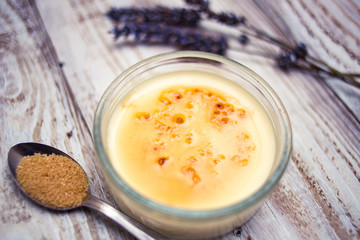 Creme brulee with lavender and sugar cane teaspoon on white woody board