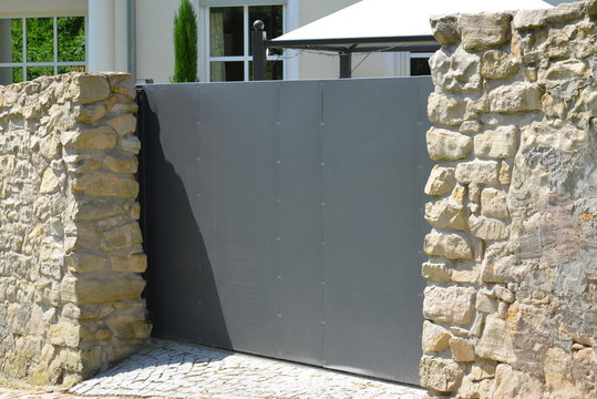 Naturstein-gemauerte Hofzufahrt eines Wohngebäudes mit Automatik-Schiebetor