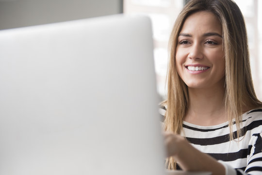 Smiling young woman using laptop