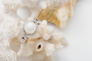Obraz na płótnie Canvas Silver ring with pearl and diamonds on coral against white background