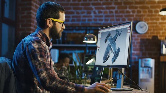 Bearded man in eyeglasses using computer and drawing graphics for video game working in office
