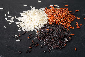 Jasmine rice, Red rice, Black rice on black stone background