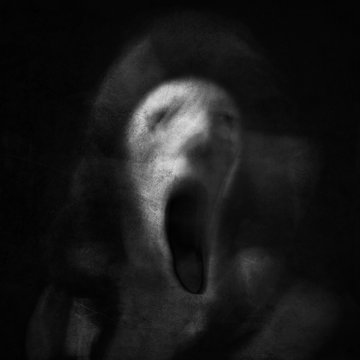 Scream of horror. Screaming ghost face. Scary halloween mask. Shot with long exposure.