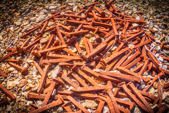 HD Cluster Of Railroad Nail Spikes Lay On Gravel Rocks.