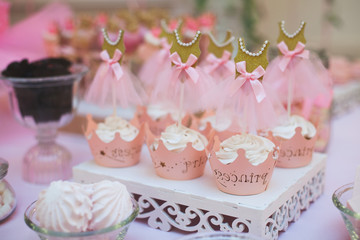 Obraz na płótnie Canvas Close up pink cupcakes fo princess with dress on the top. Delicious wedding candy bar or birthday party dessert table. Candy Bar buffet with cupcakes at restaurant.Top view