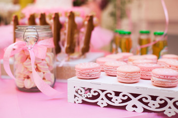 Pink macaroon on a white table horizontal.Delicious candy bar of birthday party or wedding party. dessert table. Table with colorful sweets, candies, dessert.