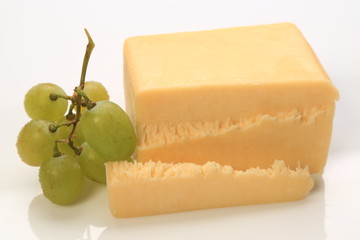 Sliced block of cheese with grapes on the side