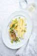 Modern German fried cod fish filet with white asparagus in hollandaise sauce und roast potatoes as top view on a plate