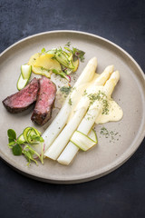 Modernes barbecue dry aged Filet Steak aufgeschnitten mit weißen Spargel in  Hollandaise Sauce und Bratkartoffel als Draufsicht auf einem Teller