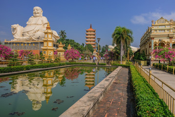 Fototapeta na wymiar Ho Chi Minh, Vietnam - January 13, 2018: Huge statue of a white Buddha reflected in a pond of a Vietnam temple