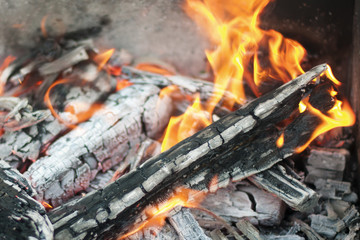 The hot coals with the tongues of flame in the old grill