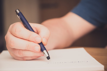 Man's hand writing on a notepad with a pen, copywriting concept