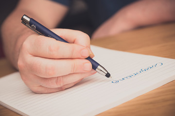 Man's hand writing on a notepad with a pen, copywriting concept