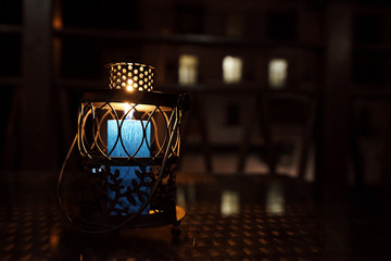 Fototapeta na wymiar A burning candle in a candlestick on the terrace in the late evening.
