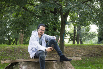 Smiling man text messaging while enjoying in coffee time at the park.