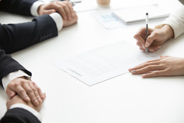 Businesswoman signing business document at group meeting, client customer puts signature on contract agreement buying services, taking bank loan, making legal partnership deal concept, close up view