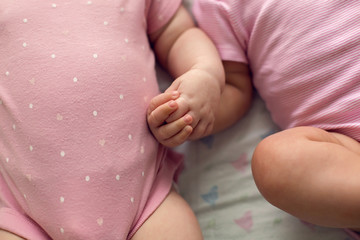 two sisters twins baby in pink clothes lying on the bed