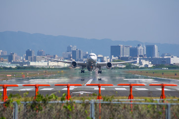 大阪の街と陽炎を背景に離陸する旅客機