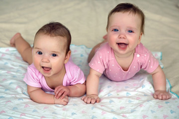 two sisters twins baby in pink clothes lying on the bed
