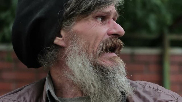 An old man or a homeless man with rotten teeth tells something, close-up