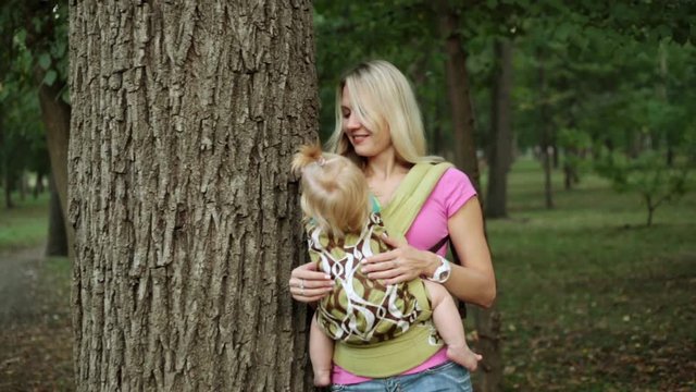 A woman with a baby in a sling or an ergo backpack.
