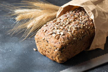 Homemade rye bread with sunflower seeds on dark board. Close up.