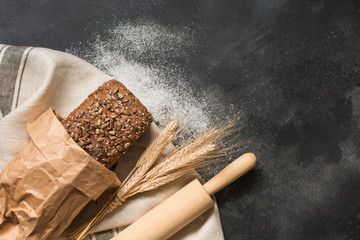Homemade rye bread with sunflower seeds on dark board. Top view. Space for text.