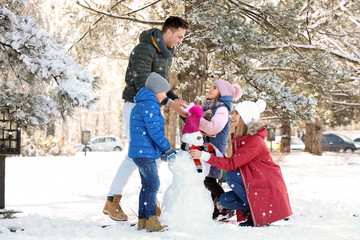 Happy family with snowman in winter park