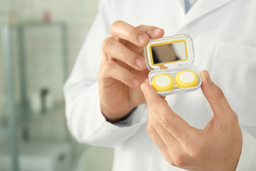 Doctor holding plastic container with contact lenses, closeup