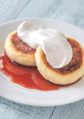 Cottage cheese patties with whipped cream and berry syrup