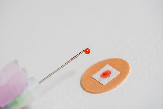 Drop of red liquid on an injection needle