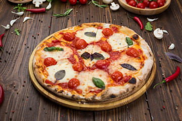 rustic italian pizza Margarita with mozzarella, cherry tomatoes and basil leaves on wooden background