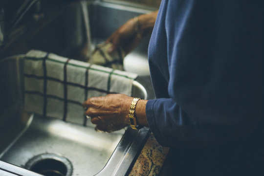 Close up of a senior woman washing dishes at home at kitchen sink